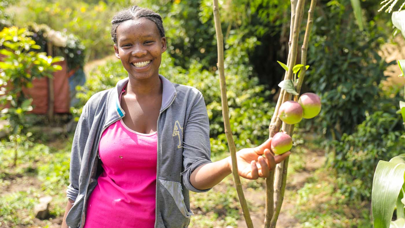 Junge Frau in Äthiopien steht bei einem Apfelbaum