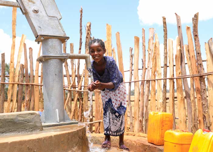 Mädchen in Äthiopien holt Wasser von einem neuen Brunnen