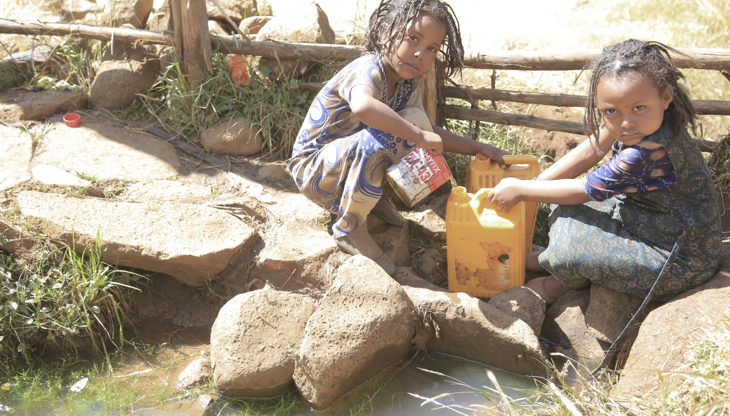 Mädchen mit einem gelben Kanister füllt Wasser ab