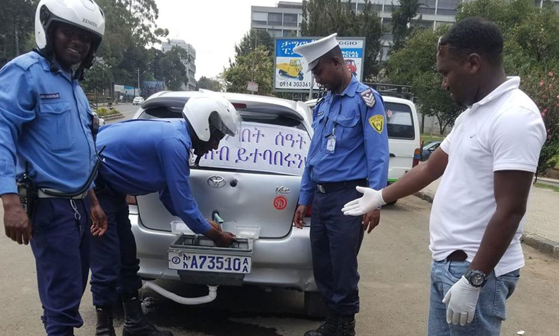Polizisten waschen sich die Hände an einer improvisierten Waschstelle auf einem Auto