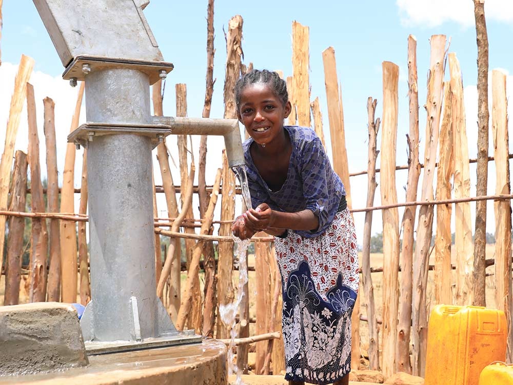 Junges Mädchen in Äthiopien pumpt Wasser aus einem sauberen Brunnen