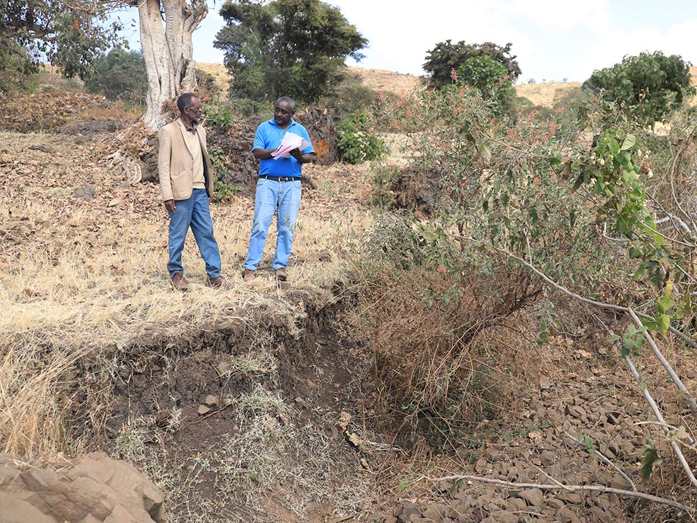 Zwei Männer stehen an einem Erosionsgraben in Äthiopien