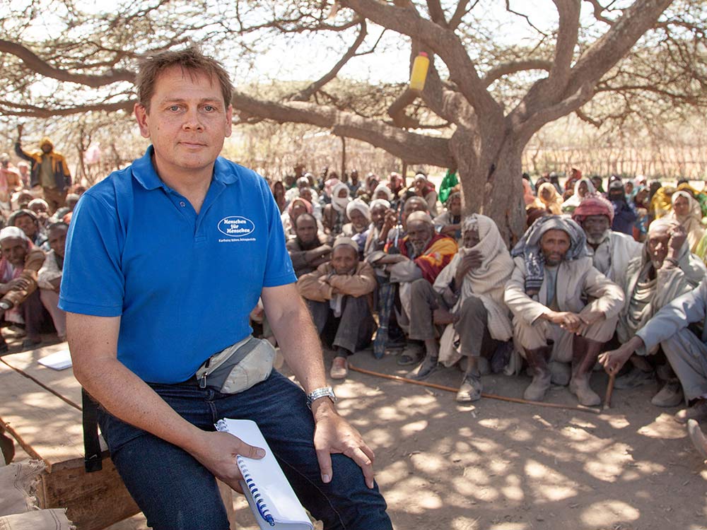 Früherer Vorstand von Menschen für Menschen, Rupert Weber, vor einer wartenden Menschenmenge in Äthiopien