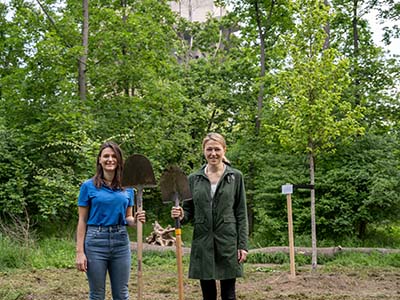 Zwei Frauen stehen vor eiem Baum.