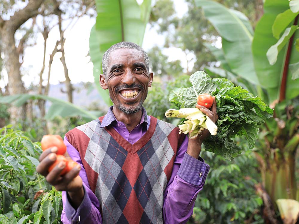 Ein Mann hält Gemüse und lächelt.