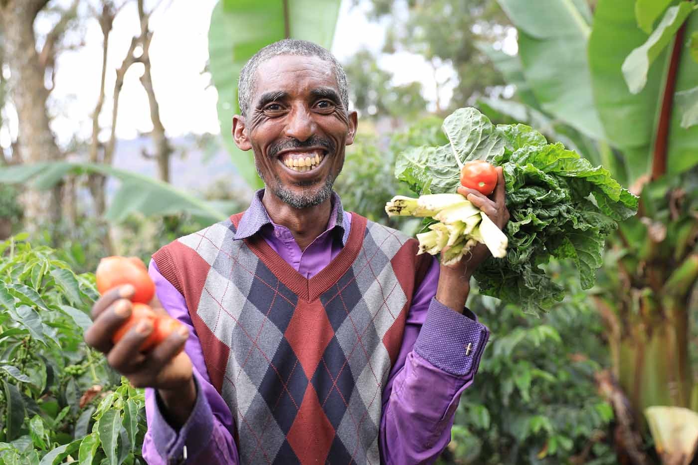 Ein Mann hält Gemüse und lächelt.