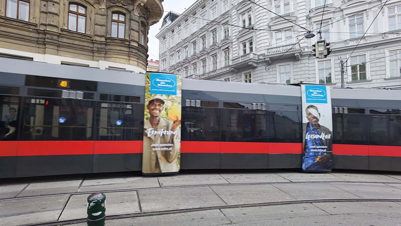 Straßenbahn in Wien mit Menschen für Menschen Werbeplakaten