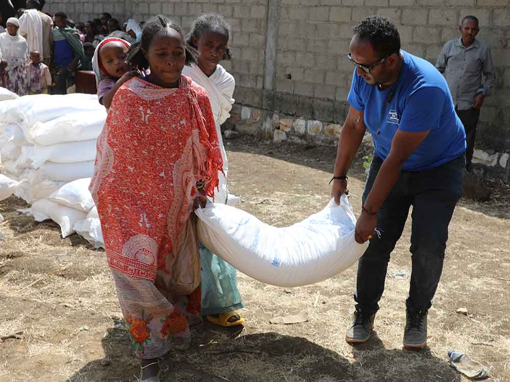 Ein Mann hilft einer Frau beim Tragen eines Getreidesackes im Rahmen einer Nothilfeverteilung in Äthiopien