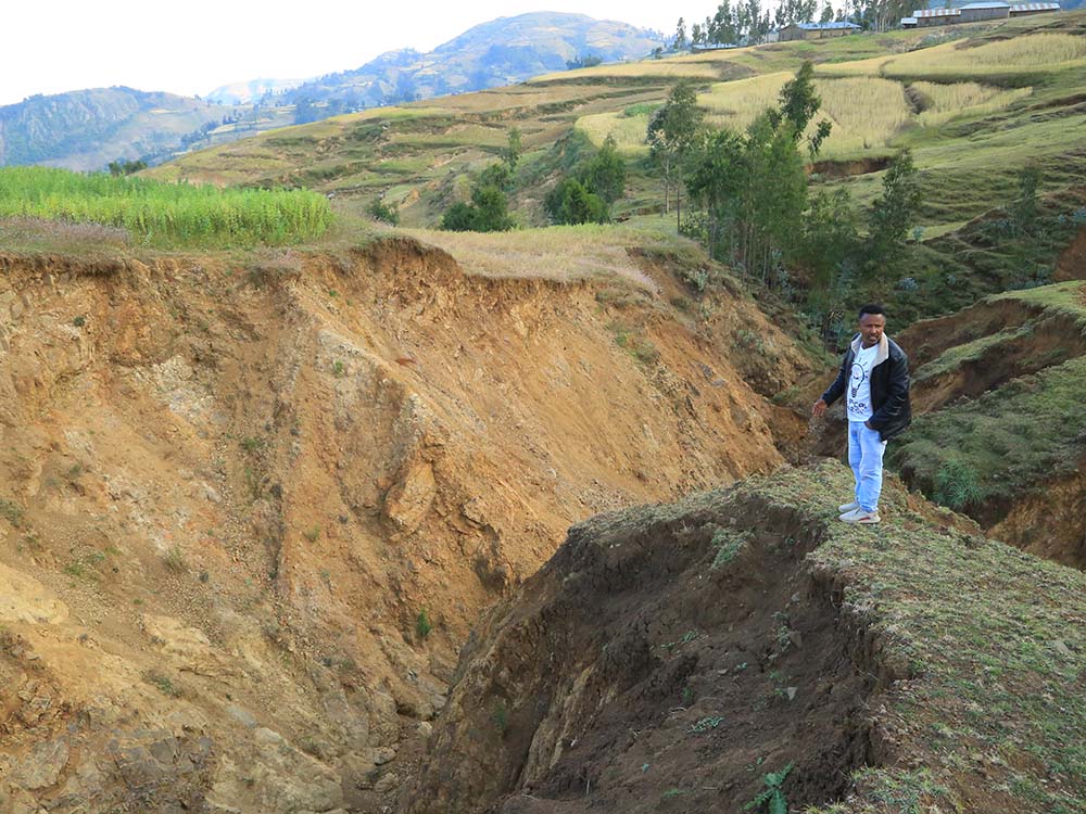 Äthiopier zeigt die großen Erosionsgräben in Albuko.