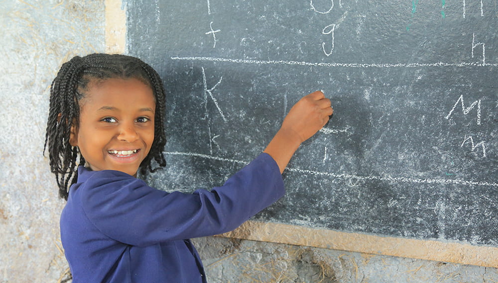 Äthiopisches Kind schreibt mit Kreide an eine Tafel