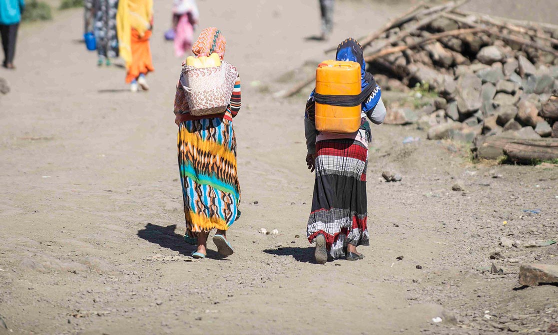 Frauen tragen Wasserkanister am Rücken