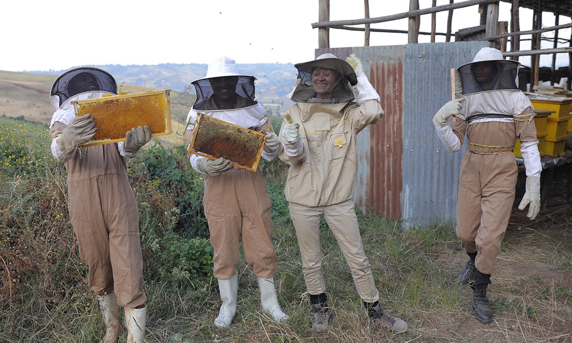 Eine Gruppe Imker präsentiert glücklich ihre Bienenwaben.