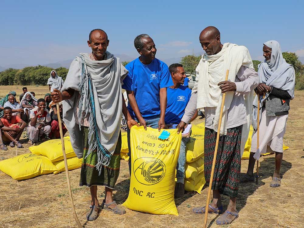Landesrepräsentant von Menschen für Menschen mit zwei äthiopischen Männern, die Hilfsgüter erhalten