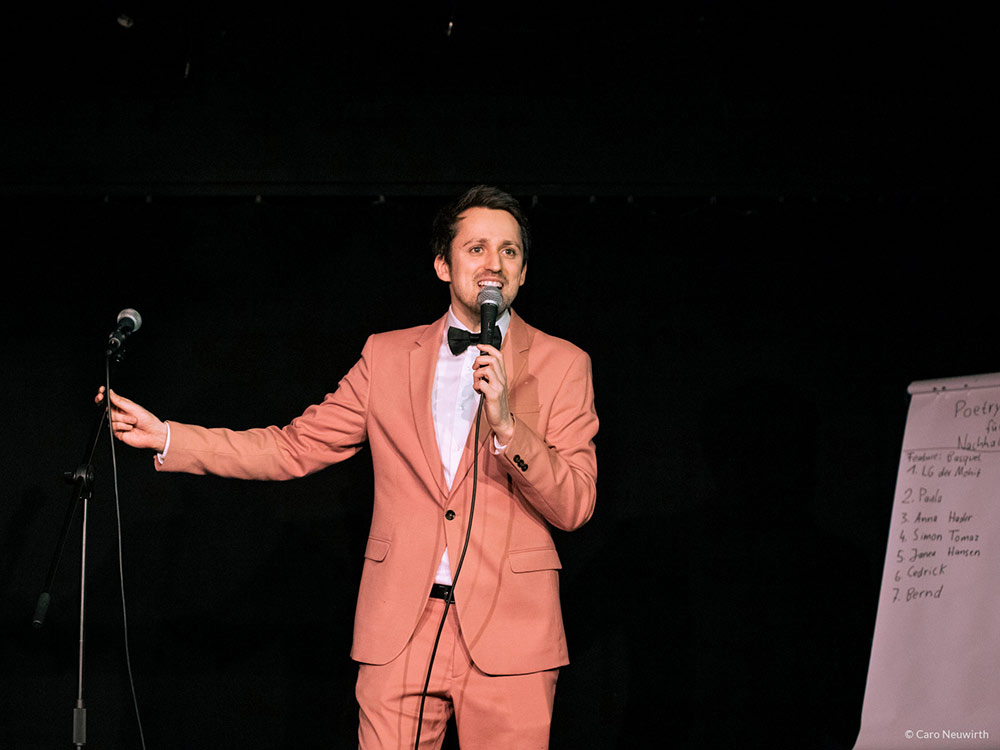 Ein Mann im lachsfarbenen Anzug auf der Bühne