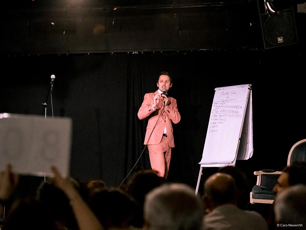 Ein Mann steht auf der Bühne und notiert auf einem Flipchart die Punkte der Publikumsjury