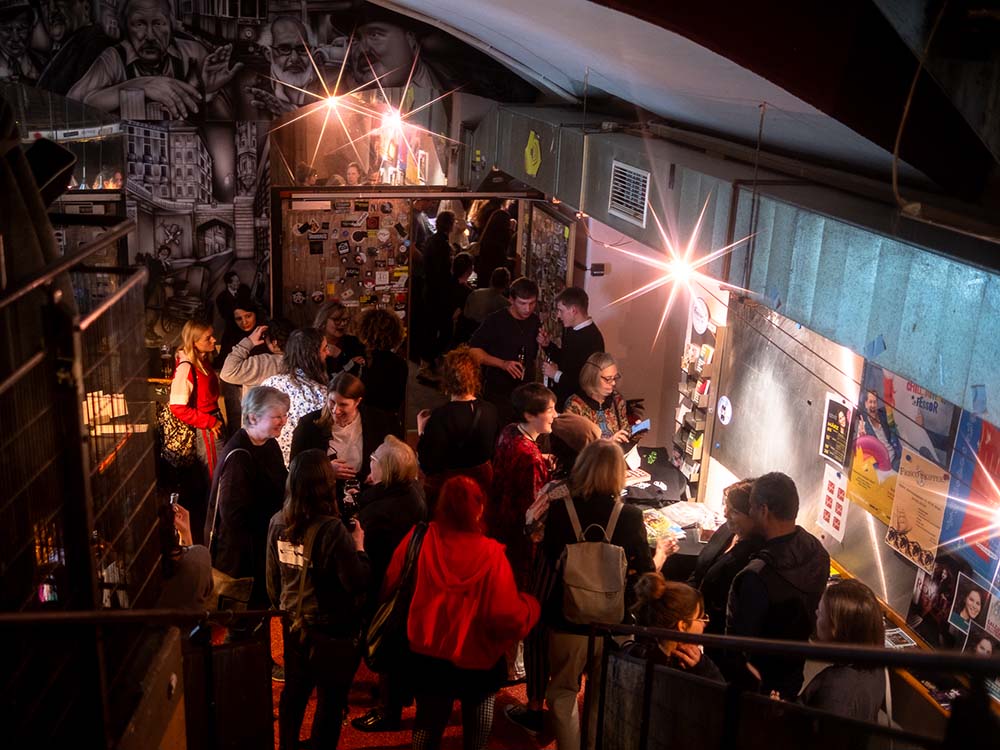 Viele Menschen stehen in einer Bar und unterhalten sich.