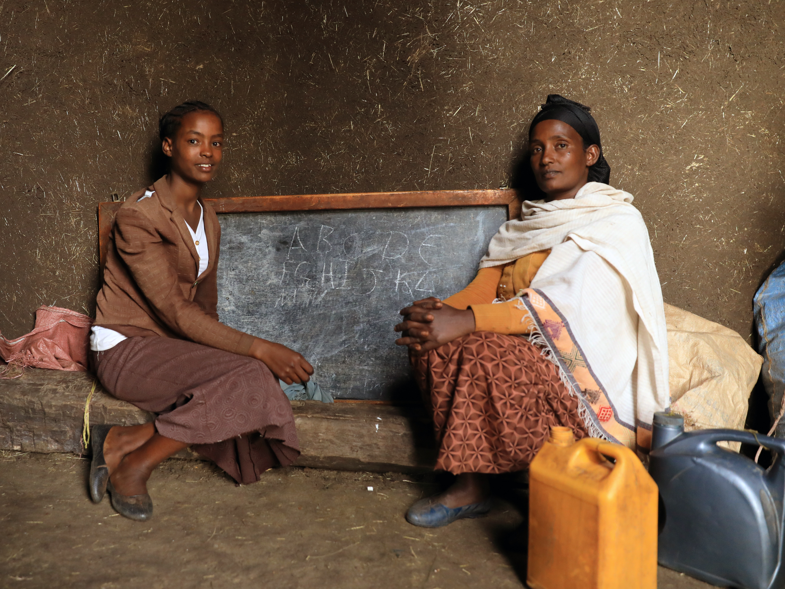 Eine Mutter und ihre Tochter sitzen vor einer Tafel