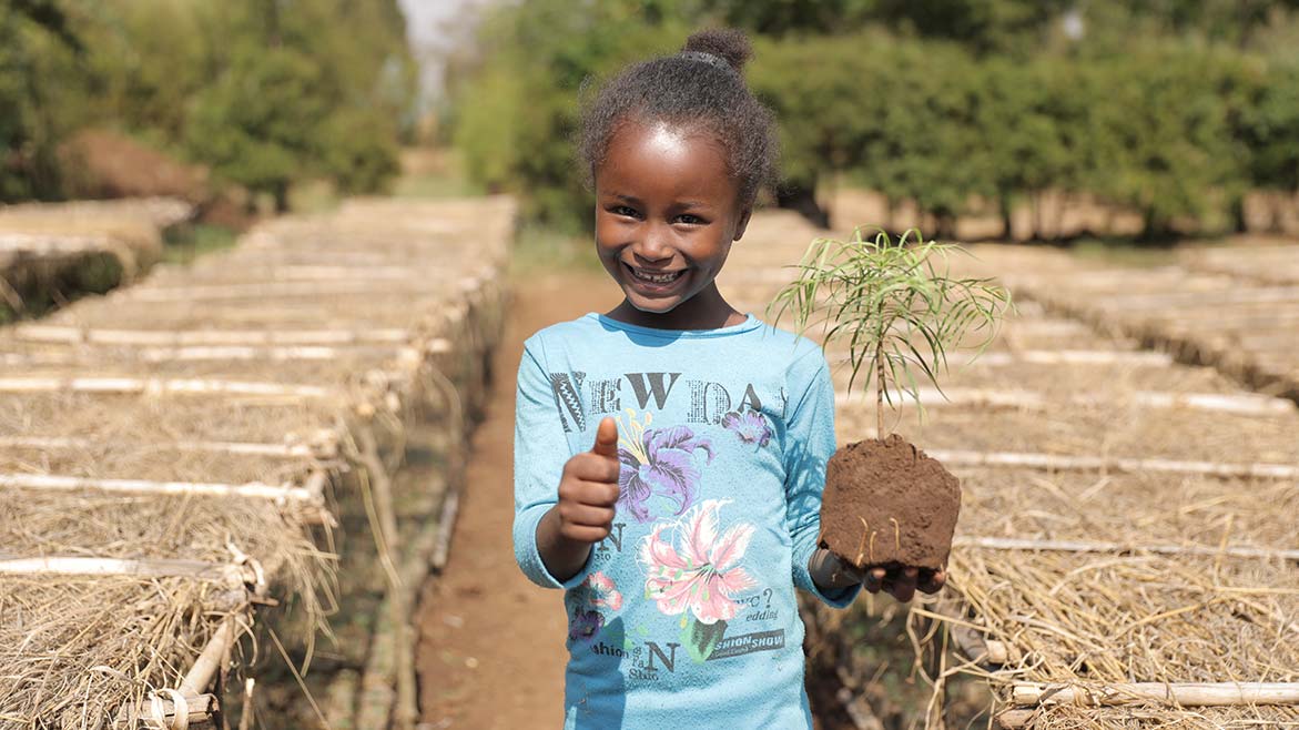 Äthiopisches Mädchen mit Baumsetzling in der Hand