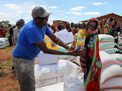 eine Frau in Äthiopien erhält von einem Mitarbeiter einer Hilfsorganisation Nahrungsmittelhilfe und hält eine Flasche Speiseöl