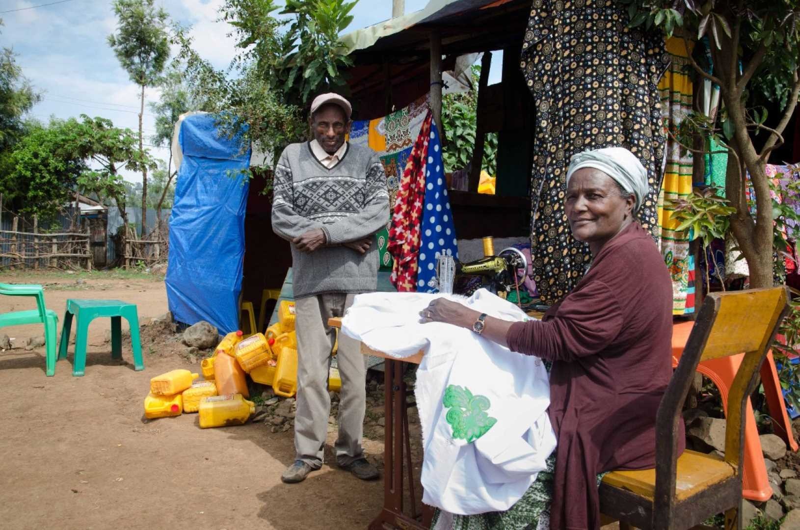 Ayinalem und ihr Mann stehen vor ihrem Zuhause und Ayinalem näht