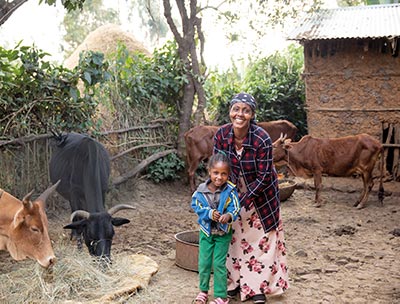 Mutter und Kind stehen in einem Gehege mit Kühen.