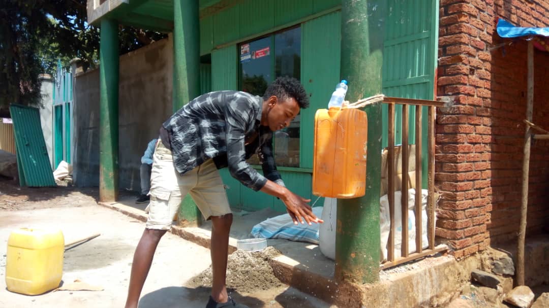 Ein junger Äthiopier wäscht sich vor einem Haus die Hände.