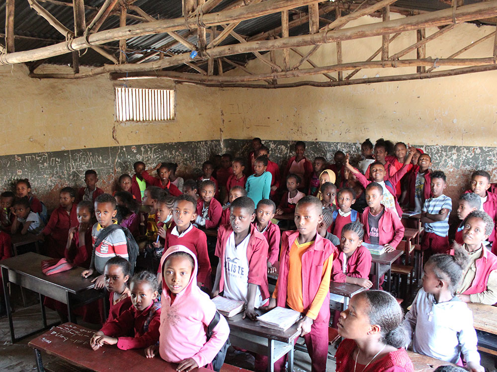 Blick in ein Klassenzimmer in Äthiopien. Am oberen Bildrand sind Holzstreben zu sehen. Etwa 40 Kinder sind in dem kleinen Raum.