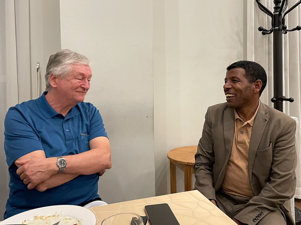 Peter Krasser und Haile Gebrselassie sitzen an einem Tisch und unterhalten sich.