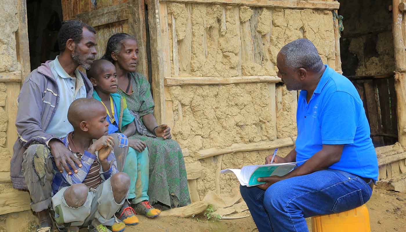 Projektleiter von Menschen für Menschen Berhanu Bedassa im Gespräch mit einer äthiopischen Familie.