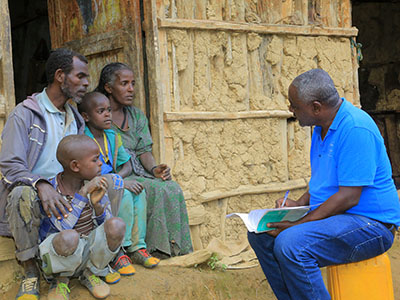 Projektleiter von Menschen für Menschen Berhanu Bedassa im Gespräch mit einer äthiopischen Familie.