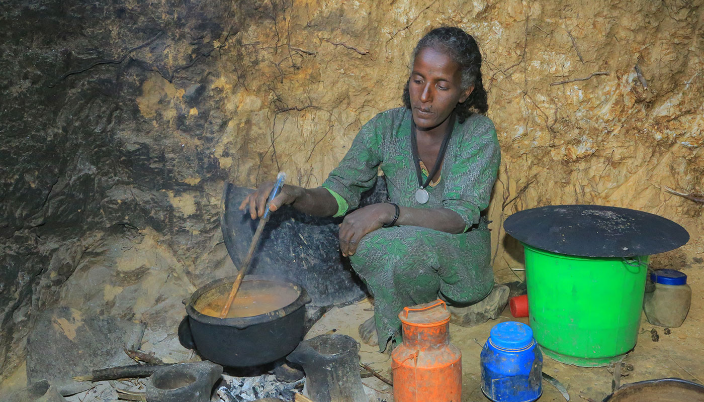 Eine äthiopische Frau kocht Soße über einer offenen Feuerstelle