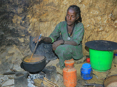 Eine äthiopische Frau kocht Soße über einer offenen Feuerstelle