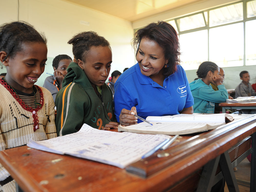 Almaz Böhm sitzt mit zwei Schülerinnen in einer neu gebauten Schule in Äthiopien