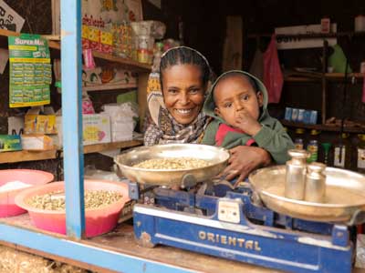 eine frau in äthiopien in ihrem laden und auf dem Arm trägt sie ihren Sohn