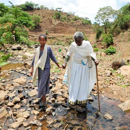 Kind führt fast blinde Oma durch einen Fluss an der Hand