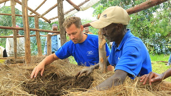 Markus Schwarz-Herda im blauen T-Shirt steht mit einem Bauern, ebenfalls im blauen Shirt und beiger Mütze, in Äthiopien an einem Wurmbeet. Die beiden begutachten den Humus.