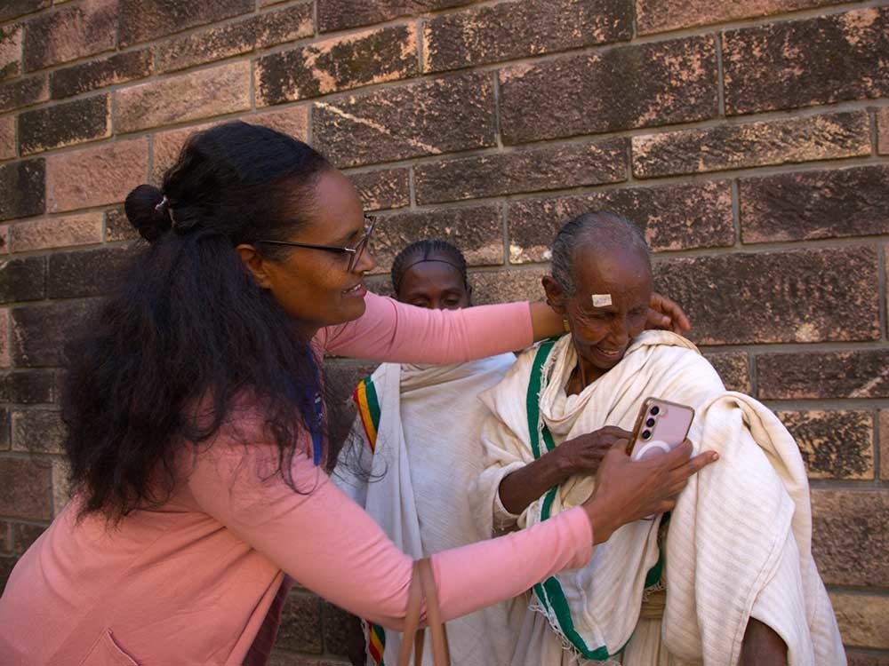 Bahritu Seyoum hilft einer Frau, eine Weste anzuziehen.