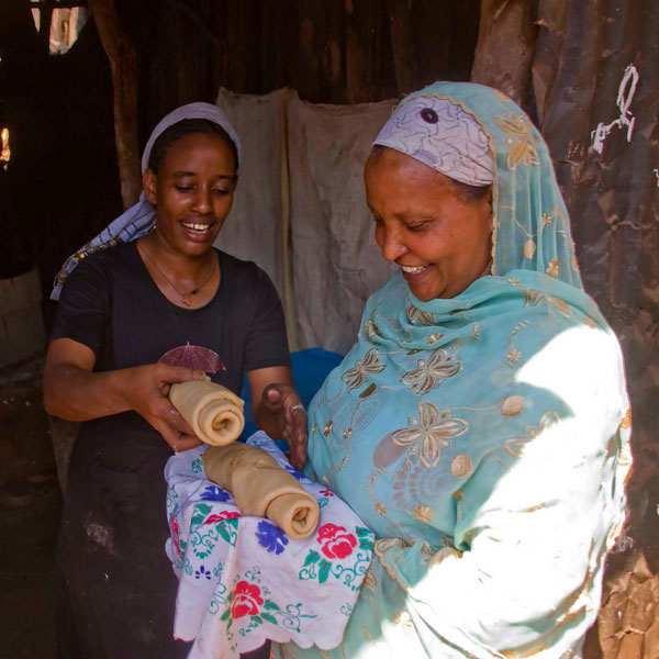 Frauen halten frisch gebackenes Injera in den Händen.