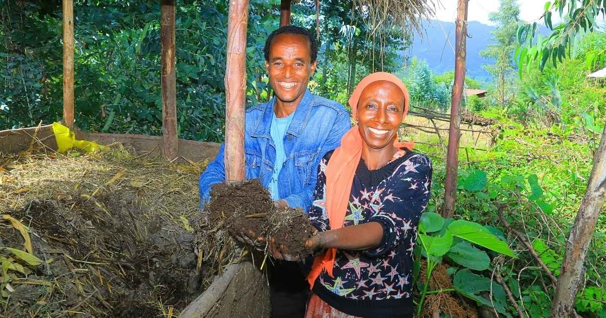 Eine Frau und ein Mann entnehmen in ihrem Garten frische Erde aus einem Wurmbeet.
