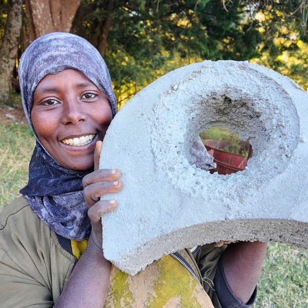 Eine Frau hält ein Teil eines Ofens aus Zement in die Kamera.