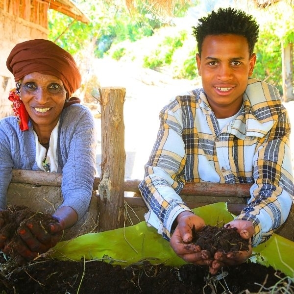 Eine Frau und ein Mann entnehmen in ihrem Garten frische Erde aus einem Wurmbeet.
