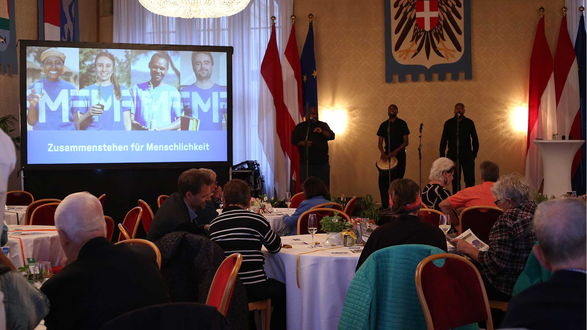 Fotoaufnahme des Veranstaltungsraumes im Wiener Rathaus mit Gästen an runden Tischen.