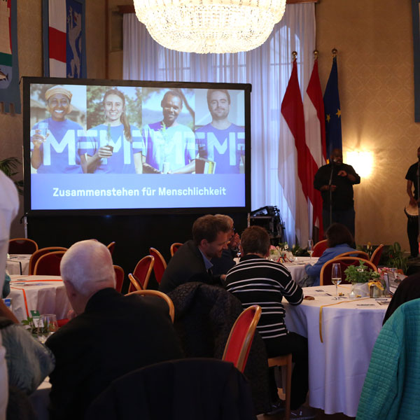 Fotoaufnahme des Veranstaltungsraumes im Wiener Rathaus mit Gästen an runden Tischen.