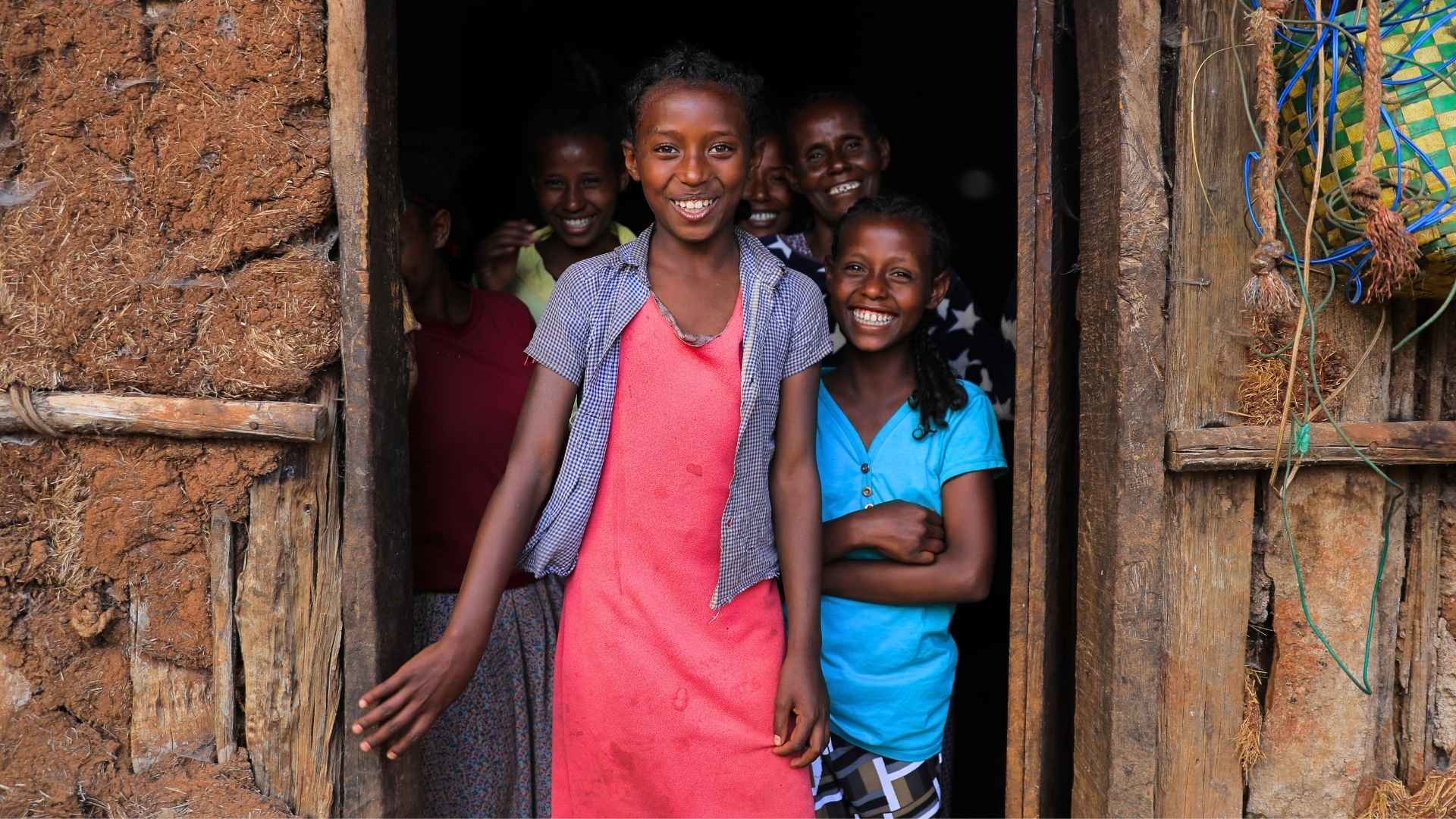 Eine Gruppe von Menschen steht im Hauseingang und lächelt in die Kamera.