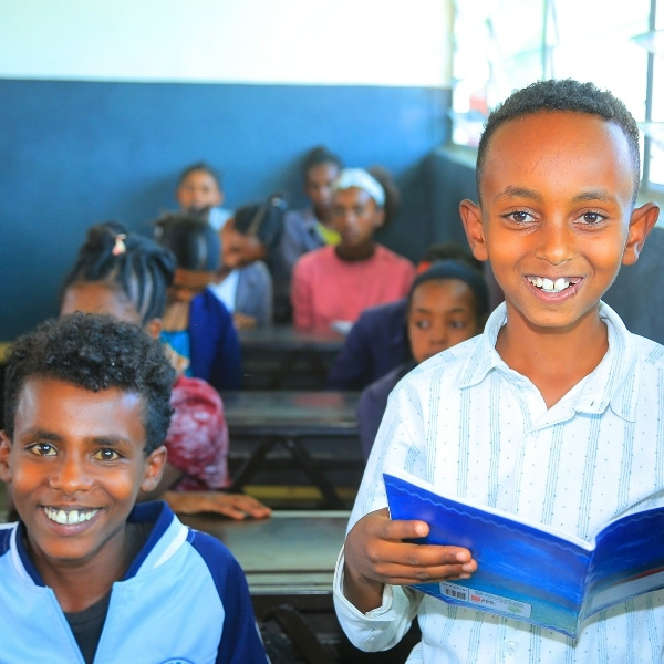 Zwei Buben sitzen nebeneinander an einem Tisch in einem Klassenzimmer.