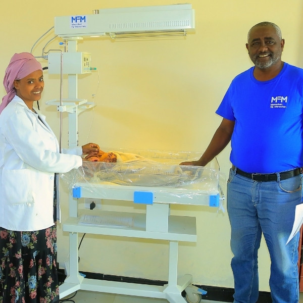 Hebamme Hayat Adem und Projektleiter Berhanu Bedassa beim kleinen Abduraman, der friedlich und geborgen unter dem Wärmestrahler schläft.