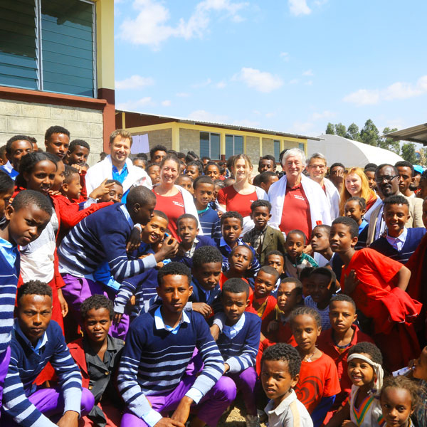 Eine Gruppe von Schulkindern und Lehrenden in traditionellen Gewändern steht vor der neu errichteten Schule in Ginchi.
