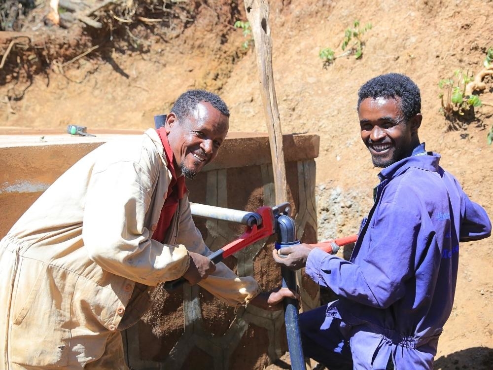 Zwei Männer setzen einen Brunnen wieder instand, damit die Dorfgemeinschaft frisches, sauberes Wasser schöpfen kann.