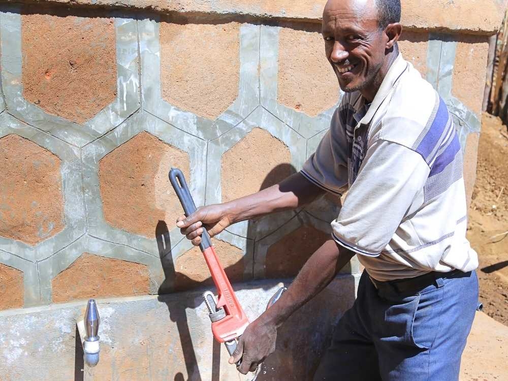 Ein Mann repariert mit einer Zange die Fassung einer Quelle.