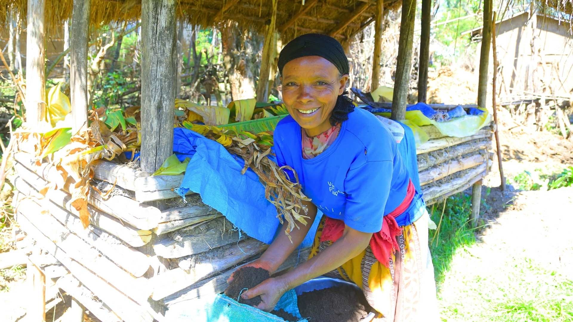 Eine Frau entnimmt aus einem Sack kompostierte Erde.